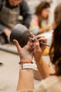 mains en train de graver une poterie en argile avec un outil artisanal