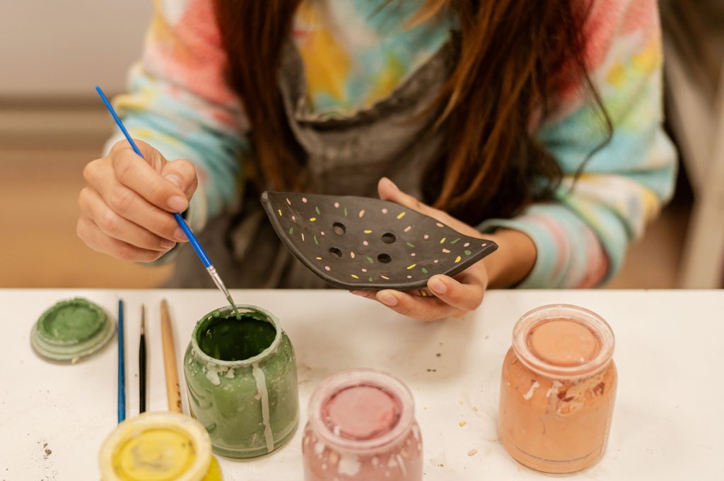 eleve en train de peindre sur de la poterie