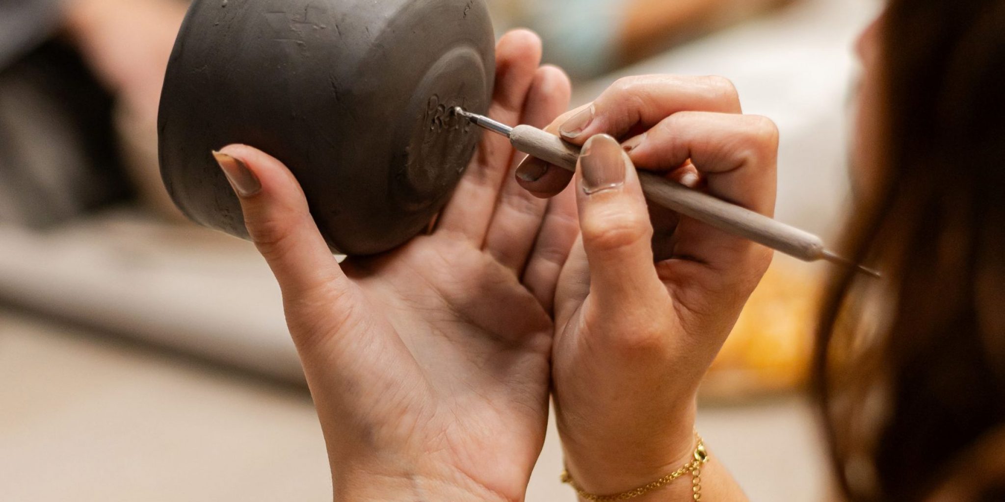 mains en train de graver une poterie en argile avec un outil artisanal